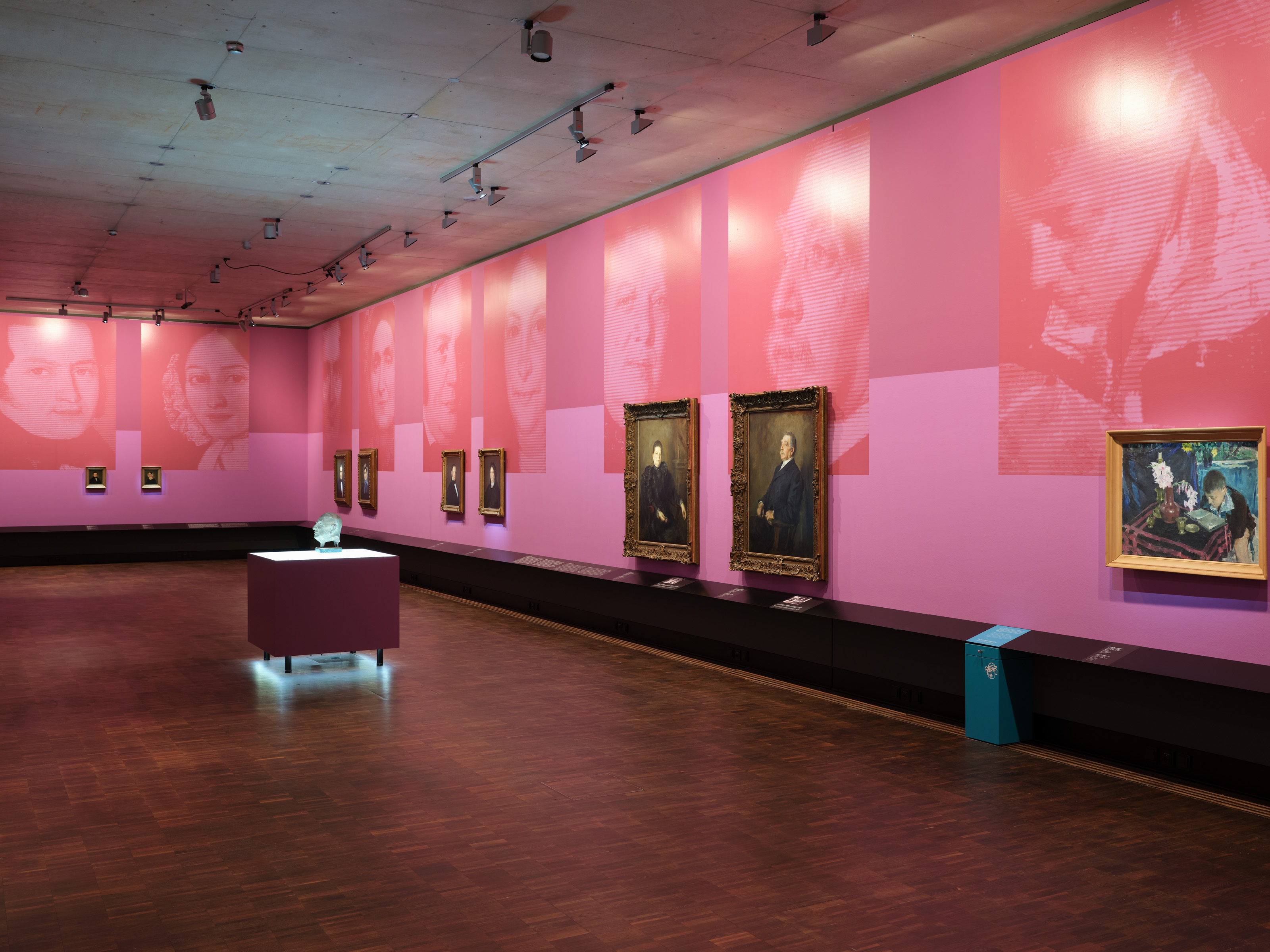 Exhibition view ""Picture Stories. Portraits of Munich Jews" - several portraits hang side by side in an exhibition room in shades of pink, large blow-ups reflect the motif of the pictures, photo: Eva Jünger / Jewish Museum Munich